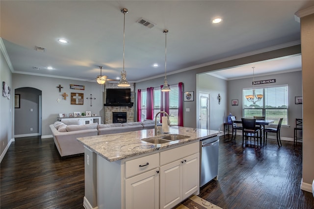 kitchen featuring sink, a stone fireplace, dark wood-type flooring, stainless steel dishwasher, and white cabinetry