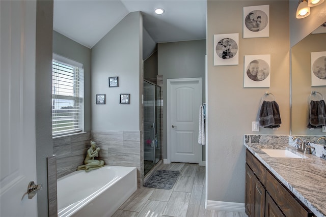 bathroom featuring tile patterned flooring, lofted ceiling, shower with separate bathtub, and vanity