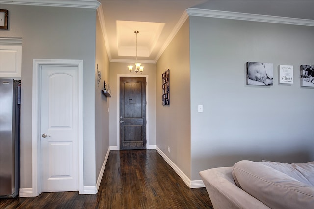 foyer featuring a raised ceiling, crown molding, dark hardwood / wood-style flooring, and a chandelier