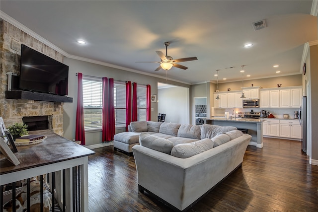 living room featuring dark hardwood / wood-style flooring, a fireplace, ornamental molding, and ceiling fan