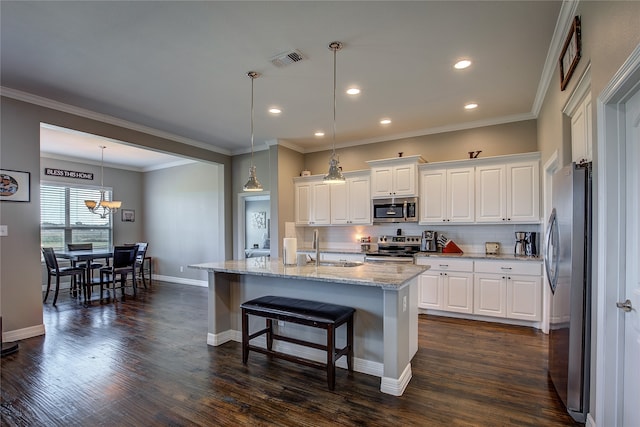 kitchen with appliances with stainless steel finishes, ornamental molding, dark hardwood / wood-style floors, and a center island with sink