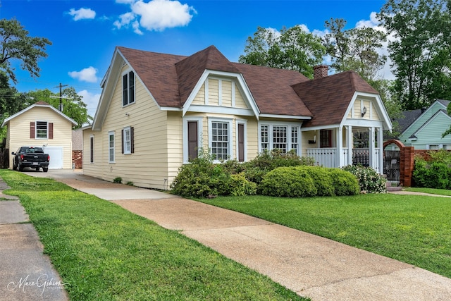 view of front of home featuring an outdoor structure, a front yard, and a garage