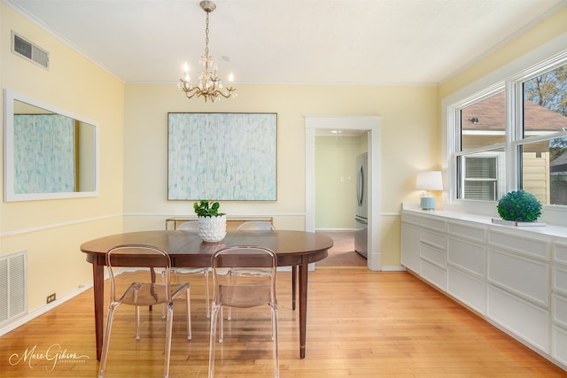 dining space with a notable chandelier, light hardwood / wood-style floors, and crown molding