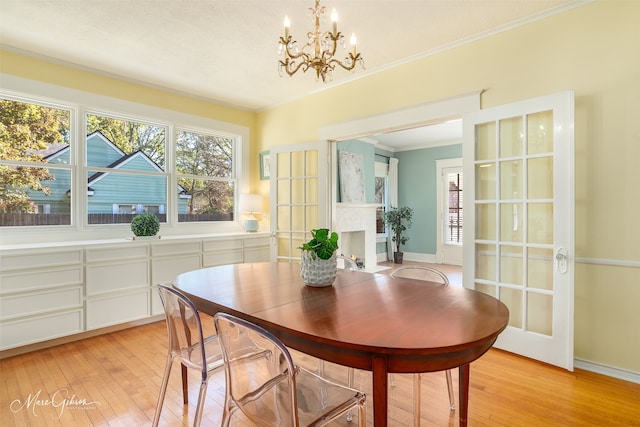 dining area featuring crown molding, french doors, a notable chandelier, and light wood-type flooring