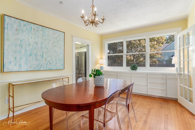 dining room featuring a chandelier, a textured ceiling, light hardwood / wood-style flooring, and ornamental molding