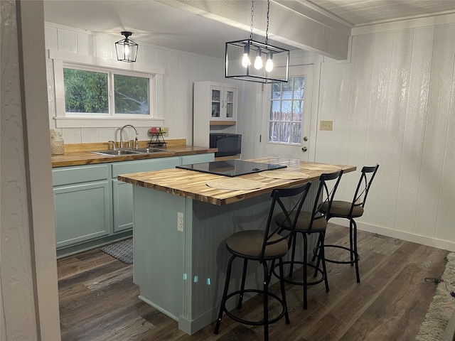 kitchen featuring dark hardwood / wood-style floors, hanging light fixtures, butcher block counters, sink, and a center island