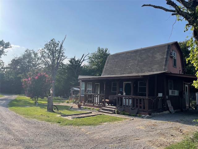 view of front of house with cooling unit, a porch, and a front yard