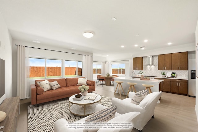 living room featuring light wood-type flooring, a wealth of natural light, and sink