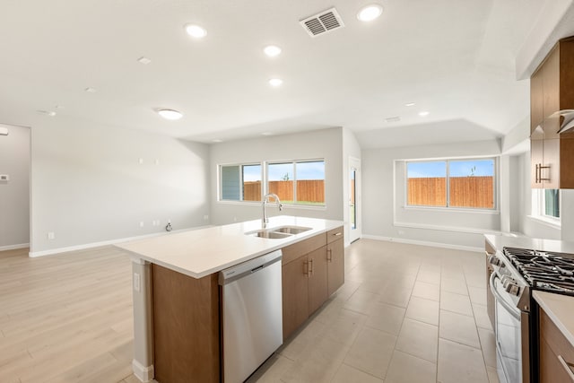 kitchen with appliances with stainless steel finishes, an island with sink, light hardwood / wood-style flooring, and sink