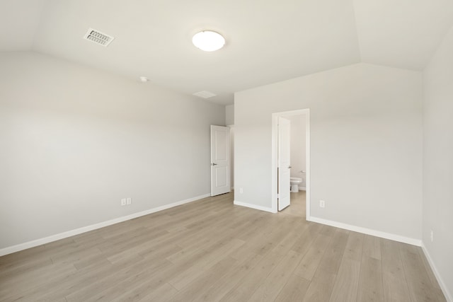 empty room with light hardwood / wood-style flooring and lofted ceiling