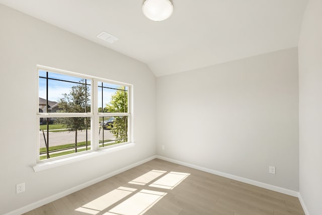 empty room with light hardwood / wood-style flooring and vaulted ceiling