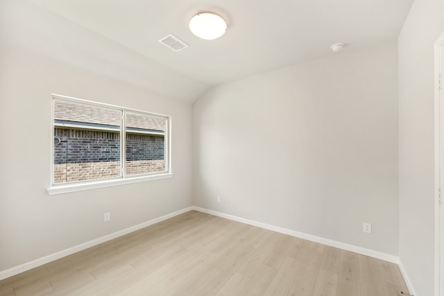 spare room featuring lofted ceiling and light wood-type flooring