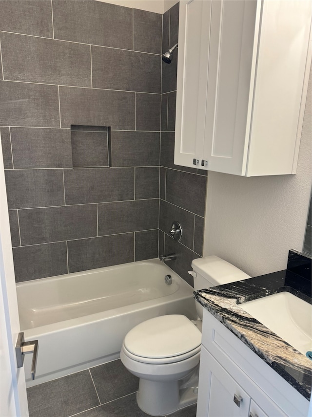 full bathroom featuring tile patterned flooring, toilet, tiled shower / bath combo, and vanity