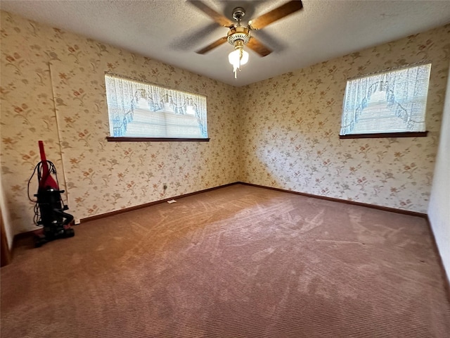 carpeted empty room with wallpapered walls, baseboards, and a textured ceiling