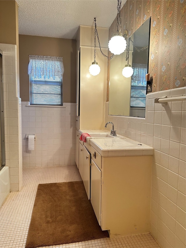 bathroom featuring a textured ceiling, vanity, tile patterned floors, and tile walls