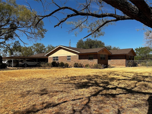 view of property exterior featuring a yard, a carport, brick siding, and fence