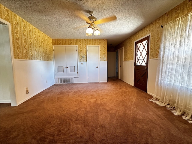 unfurnished bedroom with carpet, a textured ceiling, and ceiling fan