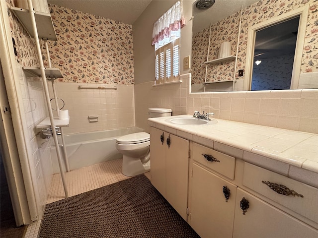 full bathroom with vanity, tile walls, tile patterned flooring, toilet, and tiled shower / bath