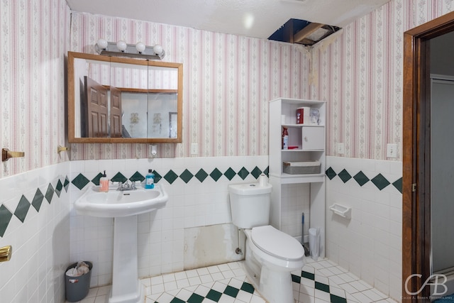 bathroom featuring toilet, tile patterned flooring, and tile walls