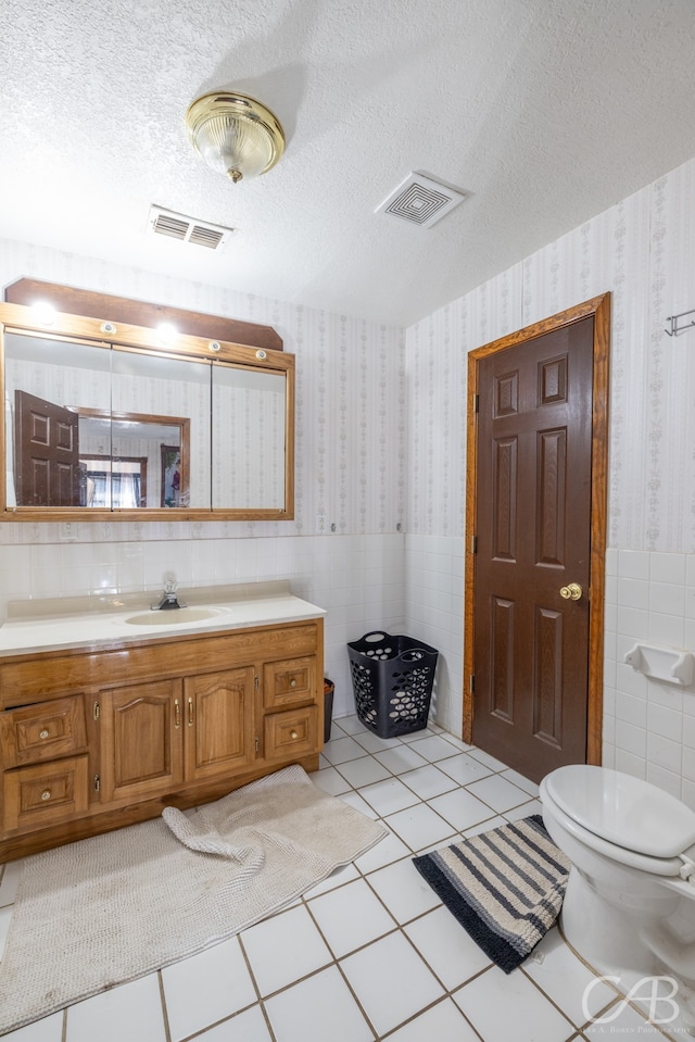 bathroom with tile walls, a textured ceiling, vanity, and toilet