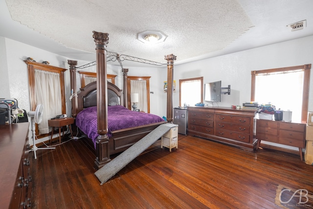 bedroom with hardwood / wood-style floors, a textured ceiling, and multiple windows