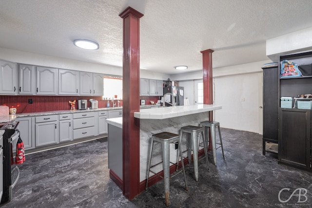 kitchen featuring a textured ceiling, appliances with stainless steel finishes, a breakfast bar, and dark tile patterned flooring