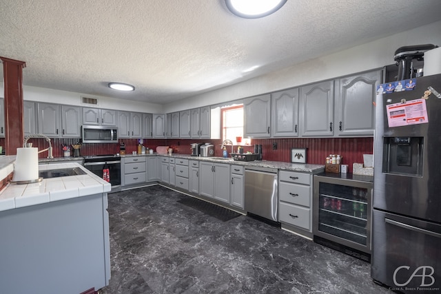 kitchen featuring sink, wine cooler, dark tile patterned floors, gray cabinetry, and stainless steel appliances