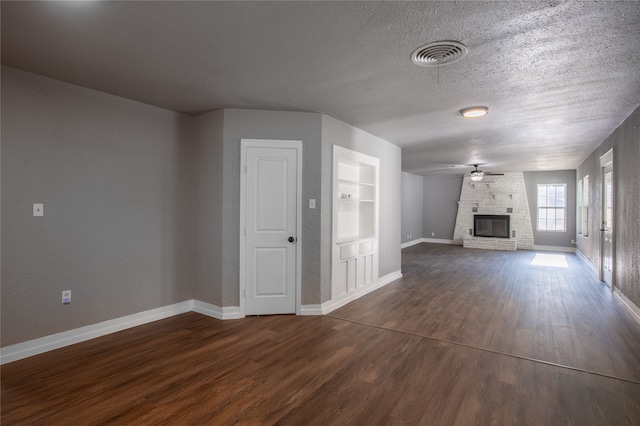 unfurnished living room featuring ceiling fan, a fireplace, a textured ceiling, and dark hardwood / wood-style floors