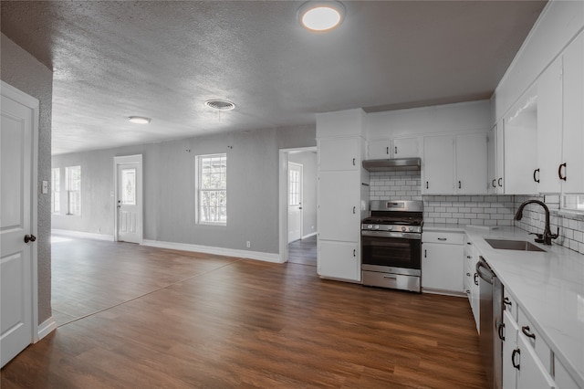 kitchen with backsplash, sink, hardwood / wood-style flooring, light stone countertops, and stainless steel appliances