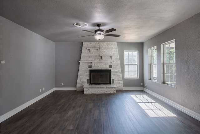 unfurnished living room with hardwood / wood-style floors, brick wall, a fireplace, a textured ceiling, and ceiling fan