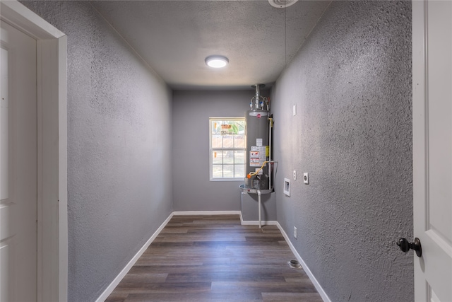 corridor featuring dark wood-type flooring, a textured ceiling, and water heater