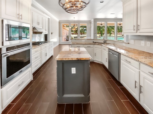 kitchen featuring a notable chandelier, dark wood-type flooring, a kitchen island, decorative light fixtures, and stainless steel appliances