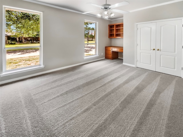 unfurnished living room with ceiling fan, ornamental molding, and light colored carpet