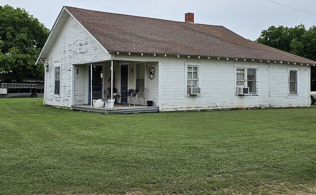 back of house featuring covered porch, a yard, and cooling unit