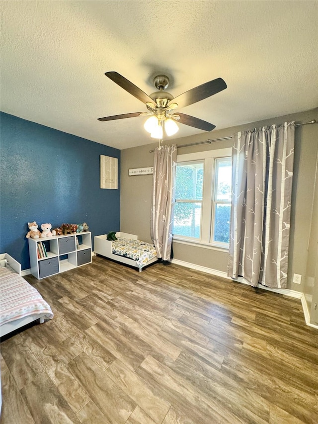 unfurnished bedroom with wood finished floors, a textured ceiling, baseboards, and ceiling fan