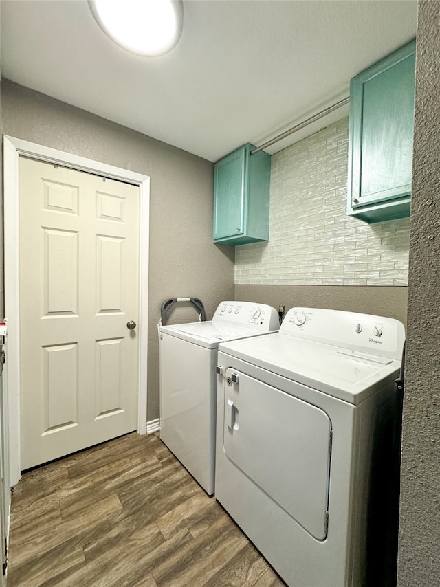 clothes washing area featuring independent washer and dryer, cabinets, and wood-type flooring