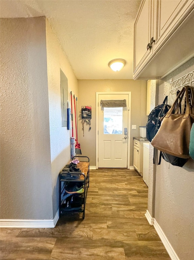 entryway featuring wood finished floors, a textured ceiling, baseboards, and a textured wall