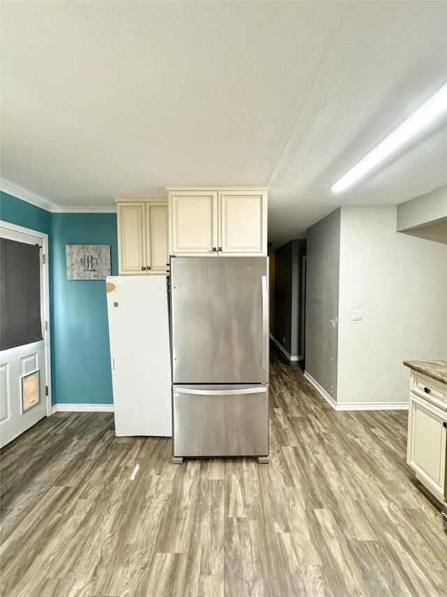 kitchen with baseboards, freestanding refrigerator, light wood-style floors, and cream cabinetry
