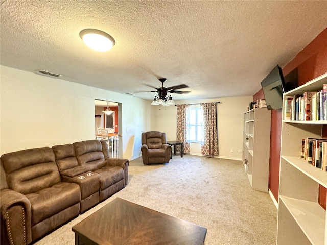 living room with light carpet, a ceiling fan, visible vents, and a textured ceiling