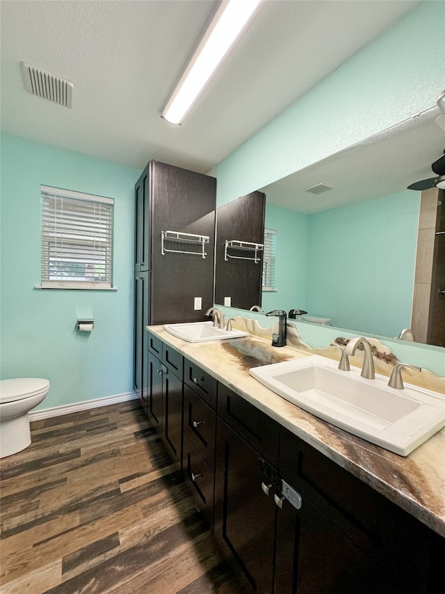 bathroom featuring double vanity, hardwood / wood-style floors, and toilet