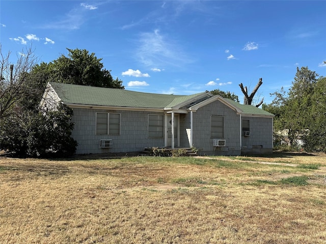 ranch-style house with a wall mounted AC and a front lawn