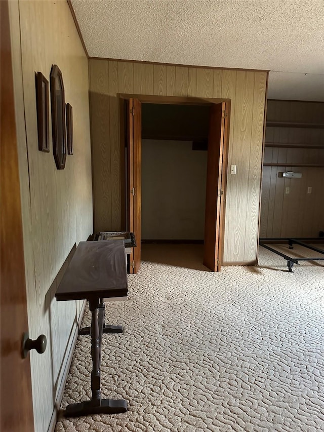 interior space with carpet flooring, a textured ceiling, and wood walls
