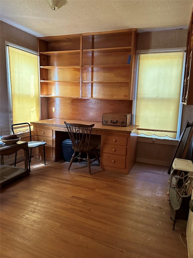 home office with wood-type flooring, built in desk, and a textured ceiling