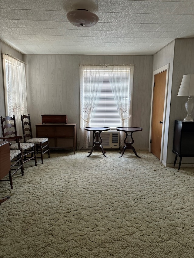 living area featuring wooden walls and carpet flooring