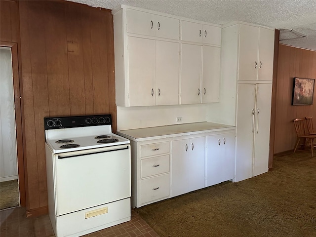 kitchen with wooden walls, a textured ceiling, white cabinets, and white range with electric stovetop