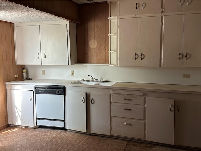 kitchen with dishwasher, sink, and wood walls