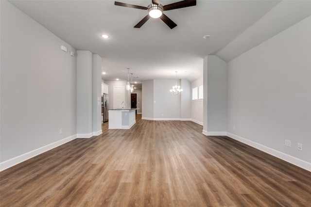 unfurnished living room with ceiling fan with notable chandelier and hardwood / wood-style flooring