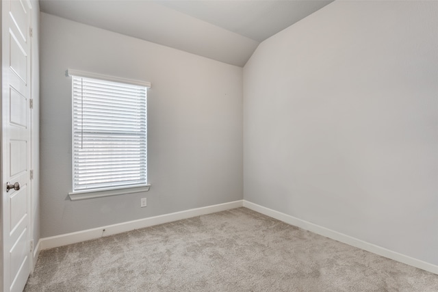 empty room with light colored carpet, lofted ceiling, and a wealth of natural light