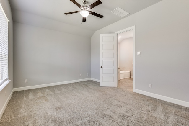 unfurnished bedroom featuring light carpet, lofted ceiling, ceiling fan, and ensuite bathroom