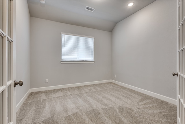 empty room featuring vaulted ceiling and light colored carpet